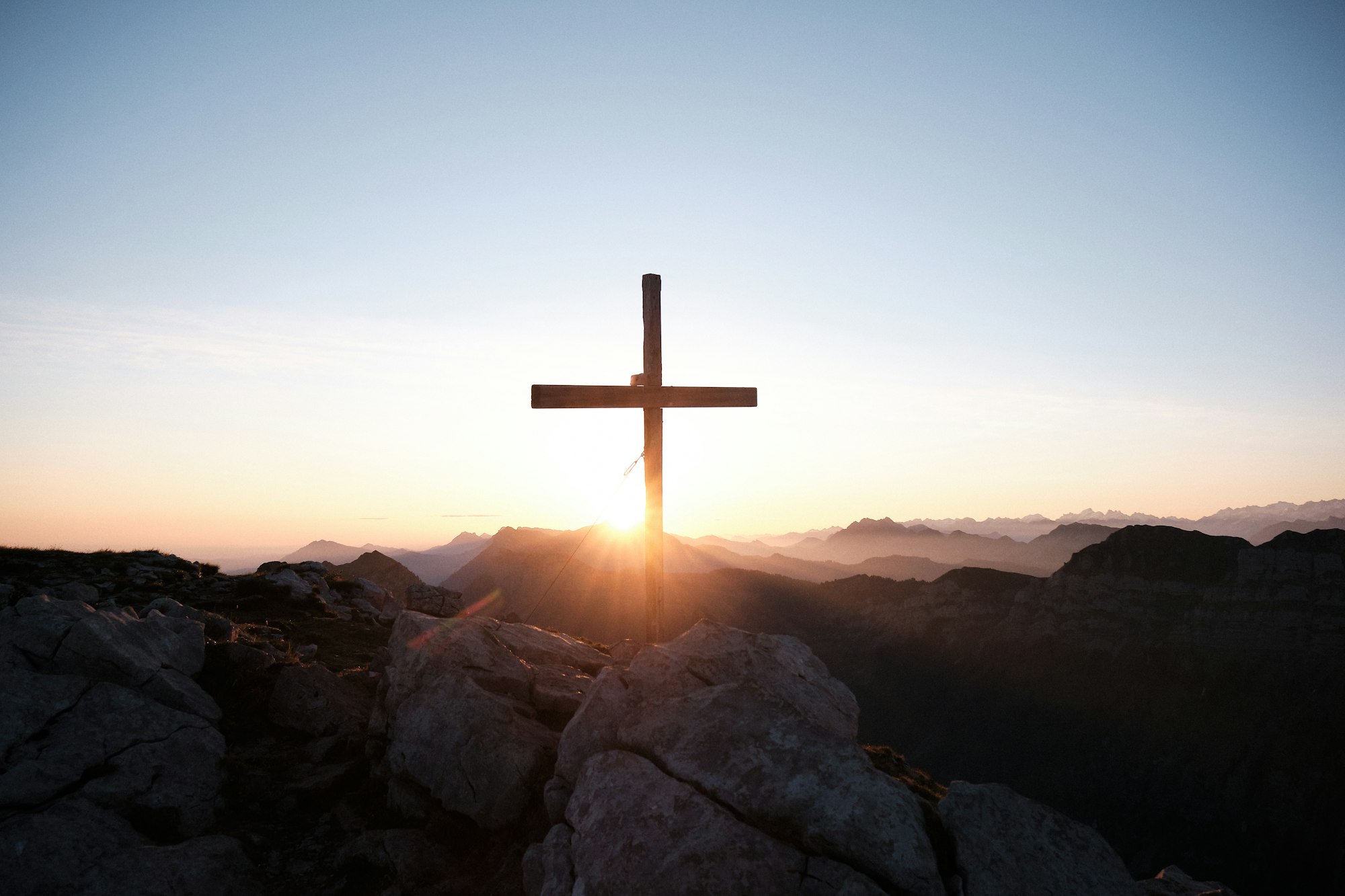 Cruz de madeira no alto de uma colina ao p&ocirc;r do sol