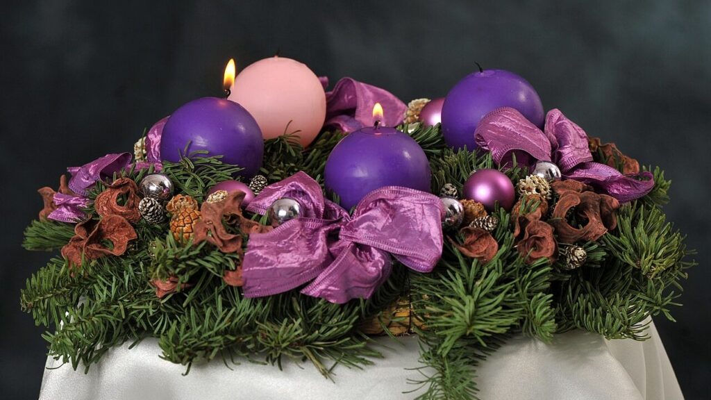 Coroa do Advento com velas roxas e uma vela rosa, símbolo da espera do Natal