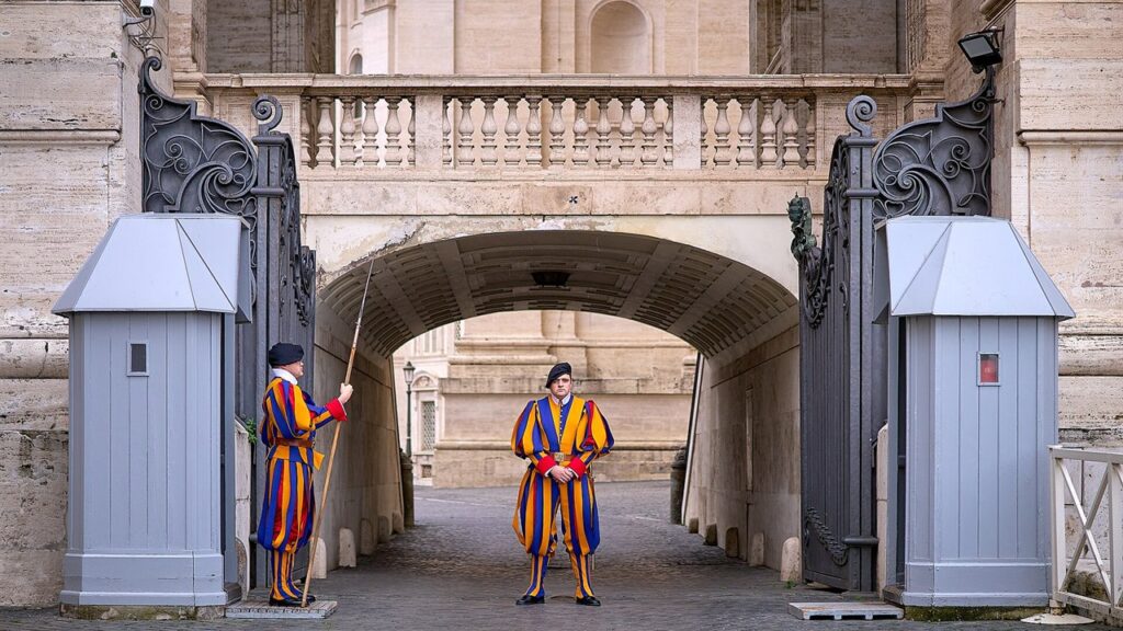 Dois guardas suíços em uniforme de gala de sentinela numa entrada da Cidade do Vaticano