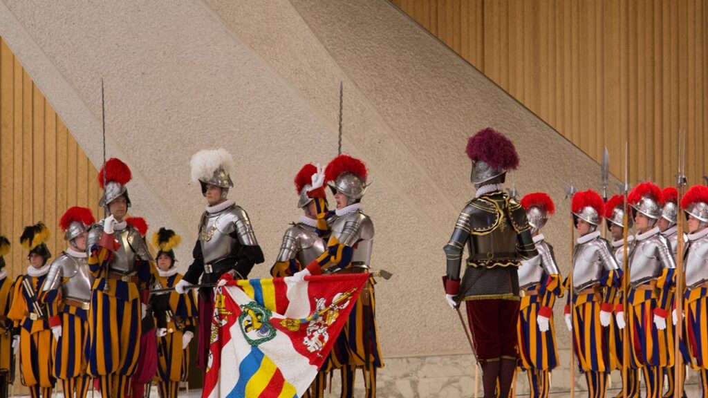 Guardas suíços de couraça e elmo com a bandeira do corpo na cerimônia de juramento de 6 de maio