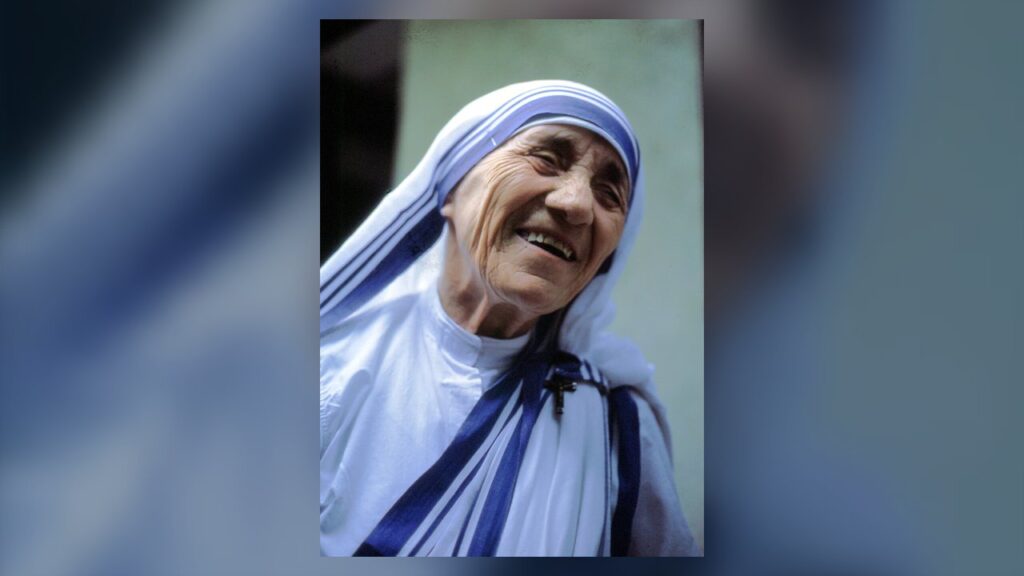 Madre Teresa de Calcutá sorrindo, com o sári branco de listras azuis das Missionárias da Caridade
