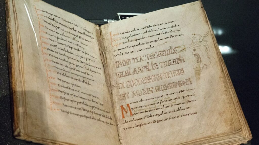 Manuscrito medieval da Regra de São Bento aberto, texto que fixa os votos dos monges