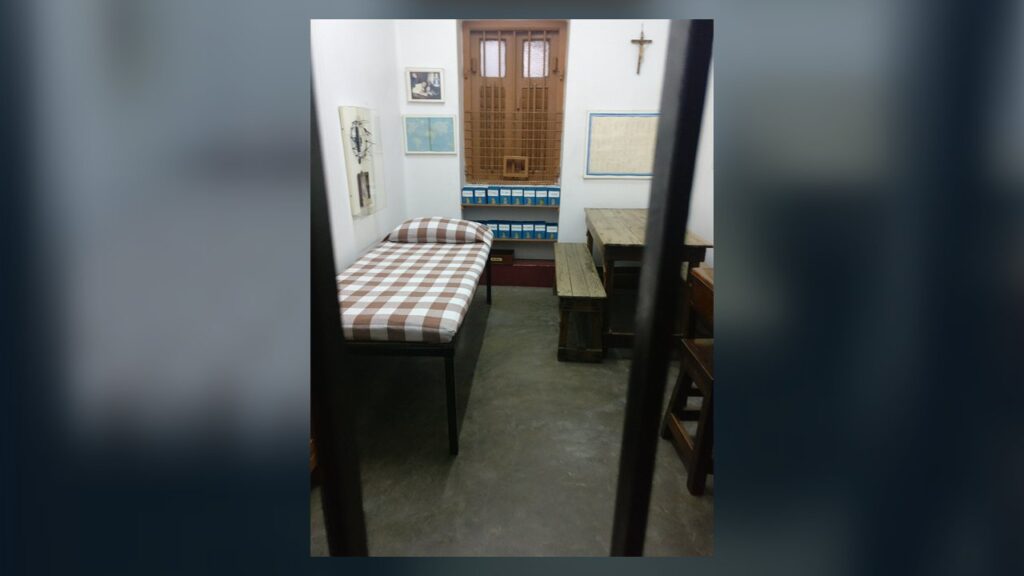 Quarto simples onde Madre Teresa viveu na Casa Mãe, em Calcutá, com cama, mesa e crucifixo