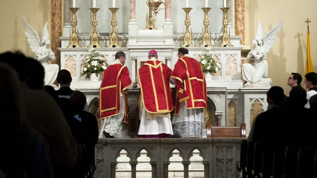 Sacerdote incensa o altar ladeado por dois ministros, no início de uma Missa solene