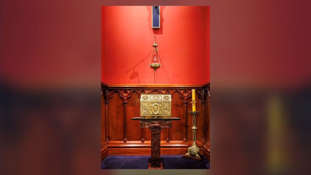 Sacrário dourado com a lâmpada do Santíssimo acesa, sinal da presença de Cristo na igreja
