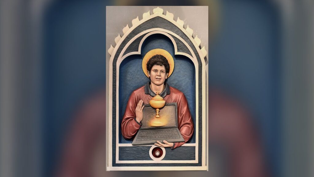 São Carlo Acutis em relevo de madeira, com um computador portátil e a Eucaristia, em igreja de Londres