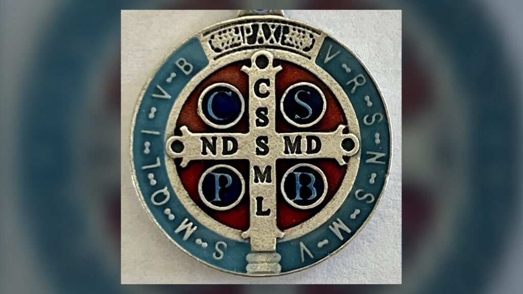 Verso da medalha de São Bento com a cruz, as letras C S S M L e N D S M D, PAX e as iniciais da borda